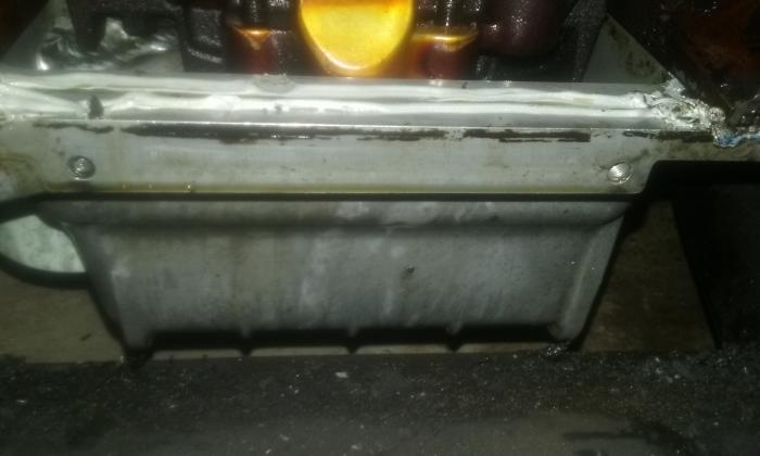 Bolt holes in front side of oil pan. This is why the timing cover is broken. See all that gray silicone?